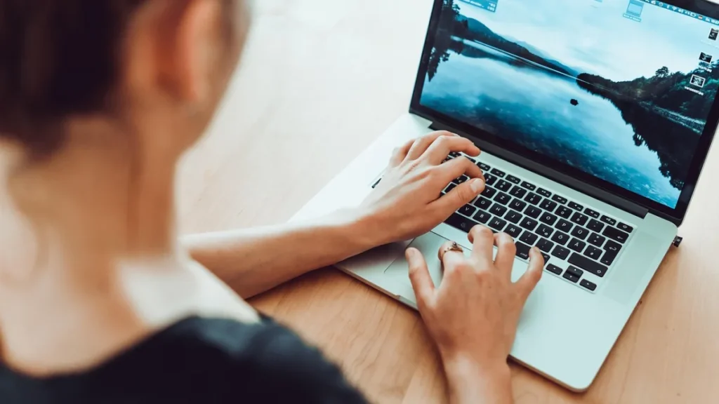 Personne travaillant sur un ordinateur portable dans un bureau, illustration des tâches confiées à un agent IA