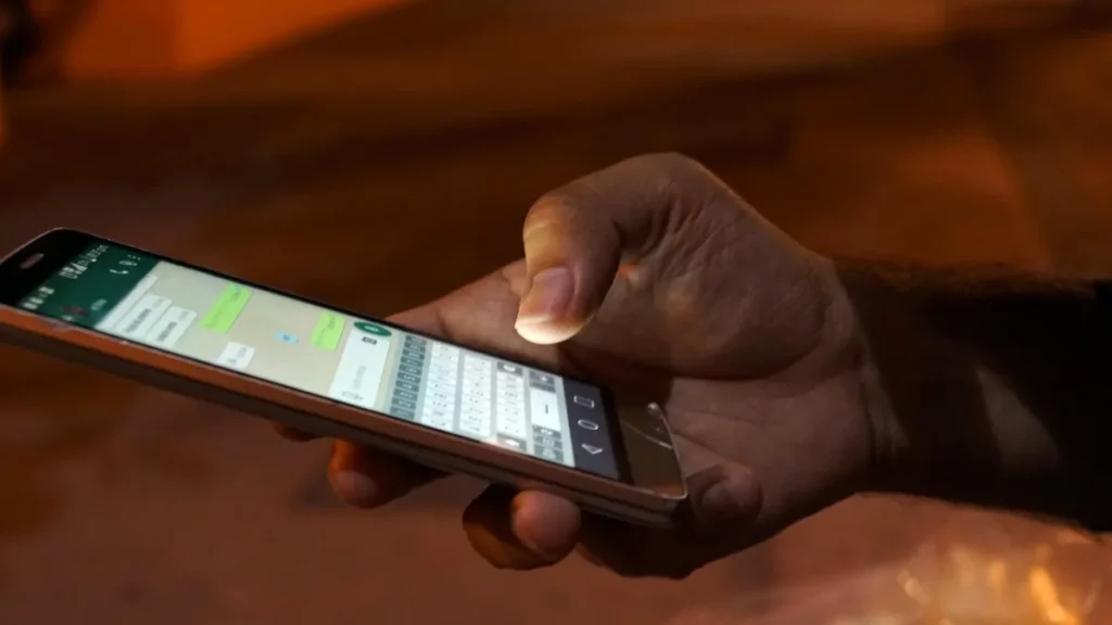 Main tenant un smartphone affichant une conversation, illustration de la recherche conversationnelle