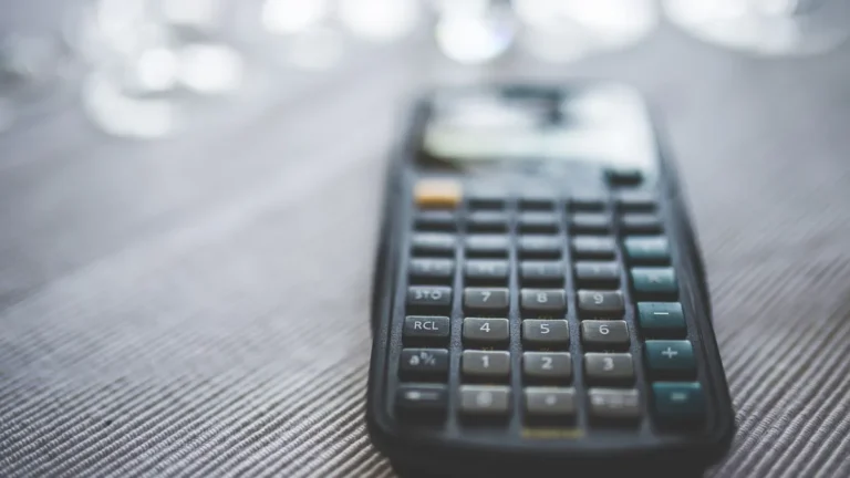 Calculatrice posée sur une table dans des tons bleu nuit, illustration du budget d'une agence GEO et de ses tarifs
